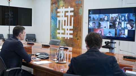 Pedro Sánchez y Salvador Illa en el despacho de Moncloa donde el pasado 25 de abril se reunieron con el comité cientifico; a la izquierda de la pantalla, el cuadro del ourensano Xesús Vázquez