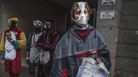 Un hombre en una protesta en Berlín contra las restricciones, con una braga a modo de mascarilla y un cartel sobre la protección.