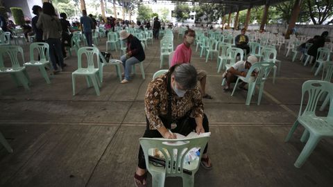 Hombres y mujeres esperan en Bangkok para solicitar ayudas del gobierno