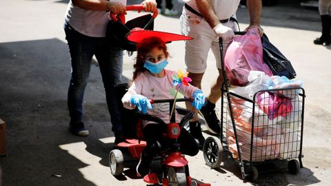 Una niña pasea con mascarilla y guantes cerca del mercado del Carmel, en Tel Aviv