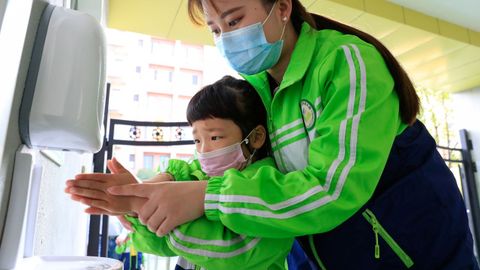 Un niño con mascarilla protectora se lava las manos en un colegio de China