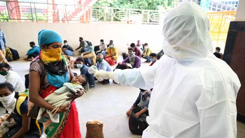Un sanitario toma la temperatura a una mujer y su hija en La India