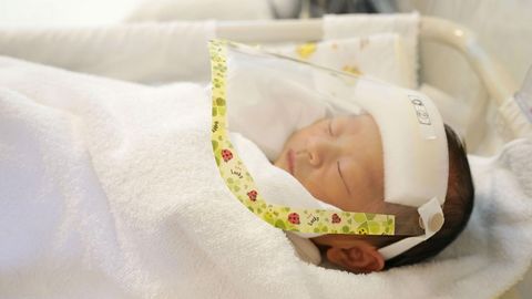 Un bebé recién nacido, con pantalla protectora en un hospital de Tokio