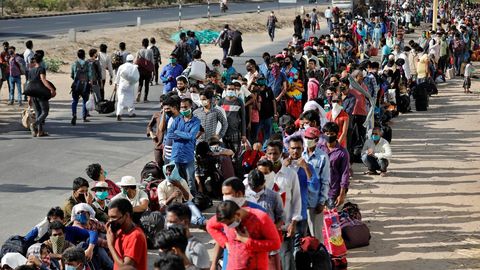 Trabajadores migrantes y sus familias hacen cola en la estación de Uttar Pradesh, en La India, para intentar regresar a sus hogares