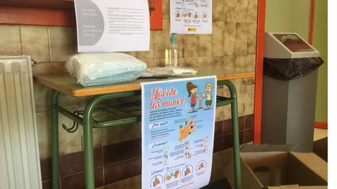 Una mesa con guantes, mascarillas y carteles, en la entrada del IES Monte Naranco