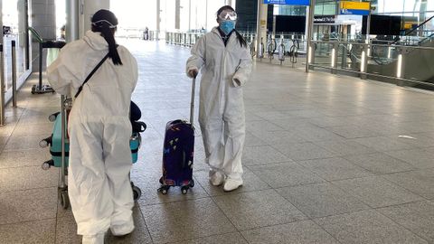 Unas pasajeras ataviadas con monos de protección en el aeropuerto londinense de Heathrow
