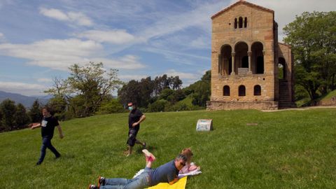 Varias personas toman el sol este domingo ante el monumento prerrománico asturiano de Santa María del Naranco en Oviedo.