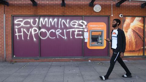 Un hombre pasa por delante de un grafiti  contra Dominic Cummings, en Londres