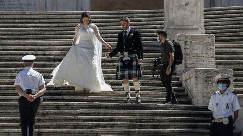 Una pareja de recién casados, él con kilt escocés, posa para su álbum de boda en la escalinata de la Plaza de España en Roma