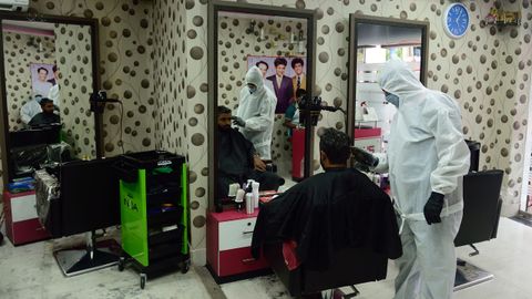 Un peluquero protegido contra el contagio, el sábado en su negocio de Kolkata, India