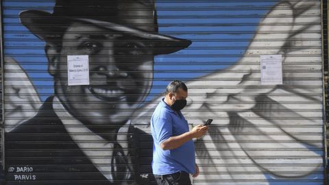 Un hombre pasea en Buenos Aires junto a una valla con un retrato de Gardel