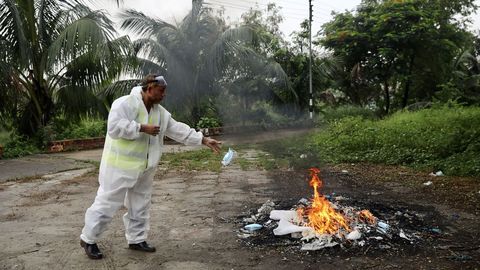 En Daca, la capital de Bangladesh, un trabajador quema su traje de protección tras asistir al entierro de un fallecido por coronavirus