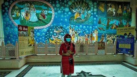 Una mujer con mascarilla visita un templo en India