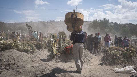 Un músico lleva su instrumento a un cementerio mexicano en el que están enterrando a fallecidos por coronavirus