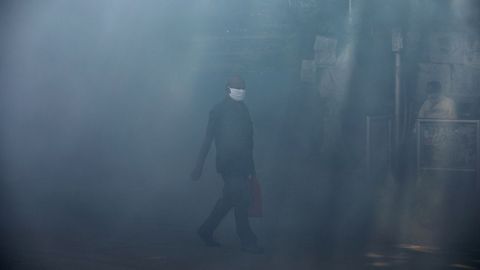 Un hombre camina por una calle fumigada en Bombai
