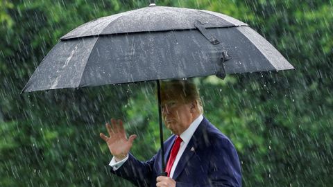 Donald Trump se protege de la lluvia, este jueves, al salir de la Casa Blanca para viajar a Dallas