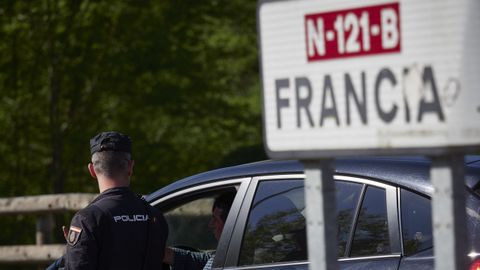 Un cartel seala la direccin a Francia mientras un polica interroga a un conductor en un control en la frontera navarro-francesa.
