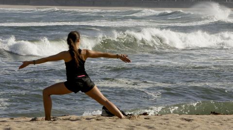 Foto de archivo de una mujer haciendo yoga en la playa