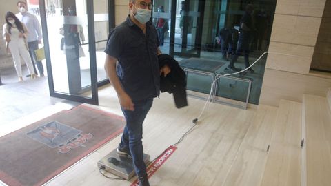 Un ciudadano entra en el Ayuntamiento de Gijn con mascarilla y tras utilizar un nuevo sistema para descontaminar zapatos de COVID-19