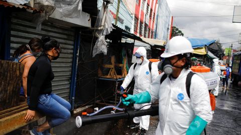 Trabajadores municipales desinfectan los puestos callejeros para comenzar a atender a los clientes a medida que la economía se reabre mientras continúa el brote de la enfermedad por coronavirus, en el centro de San Salvador, El Salvador