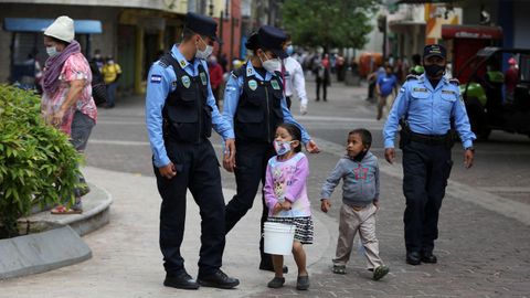 Policías hondureños hablan con dos niños mientras brindan seguridad en el Parque Central este miércoles, en Tegucigalpa, Honduras