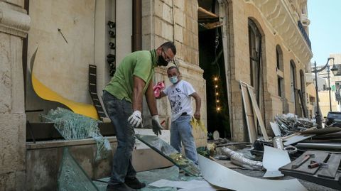 Trabajadores recogiendo cristales rotos de una tienda tras la explosión