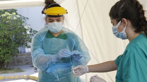 Personal sanitario en la carpa para realizar las pruebas PCR a personas desde su coche, instalada en la entrada de urgencias del hospital Gil Casares