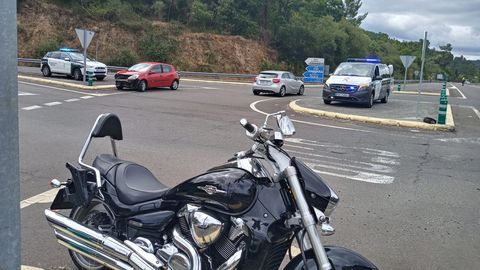 La moto en la que iban los heridos y, al fondo, el vehículo que impactó contra ella