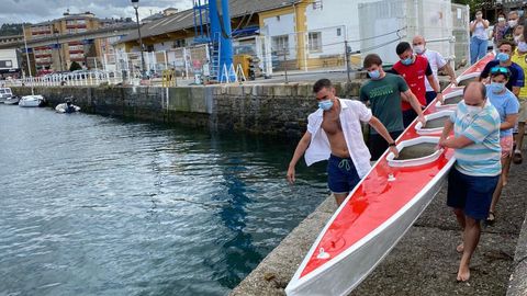 Varias personas traslsadan la canoa Virgen de la Barca hacia la ría de Navia