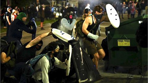 Manifestantes se protegen con escudos caseros de las balas de goma y gases lanzados por la policía en Kenosha