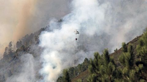 Un helicóptero entre el humo del frente del incendio más cercano a la carretera Quiroga-Folgoso