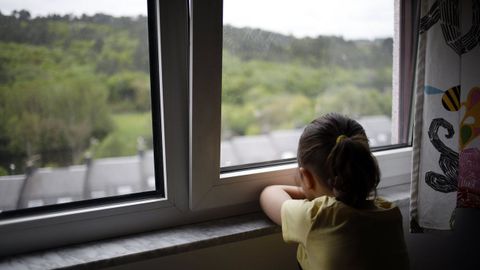 Una niña mira por la ventana durante el confinamiento