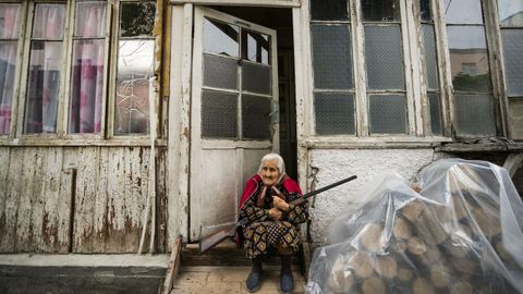 Una mujer sostiene una escopeta en la entrada de su vivienda, en la capital de Nagorno Karabaj