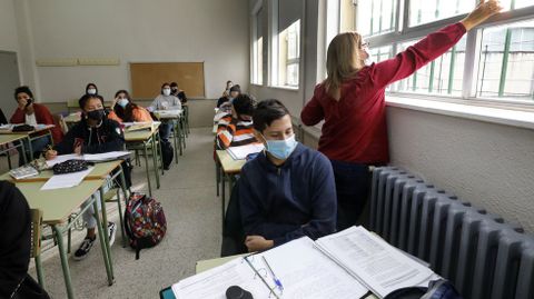 Una profesora abre las ventanas para ventilar un aula de secundaria