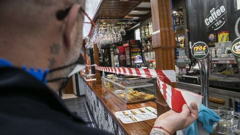 Un hostelero de Noia precinta la barra, en las que no se puede consumir desde ese jueves en Galicia