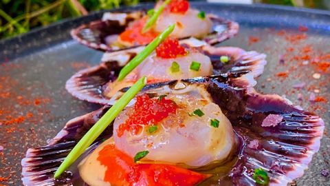 Junto a la emblemática Plaza de María Pita, en un comedor donde nos rodean la piedra y la madera, el chef coruñés nos firma estas zamburiñas marinadas en agua de mar, lima y kombu con huevas de trucha y escamas de sal de vino mencía. Producto tradicional con ingredientes muy actuales.