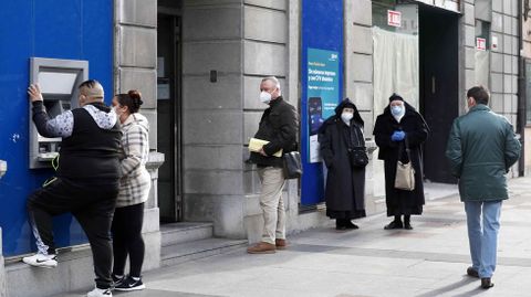 Varias personas esperando ante una entidad bancaria en Oviedo