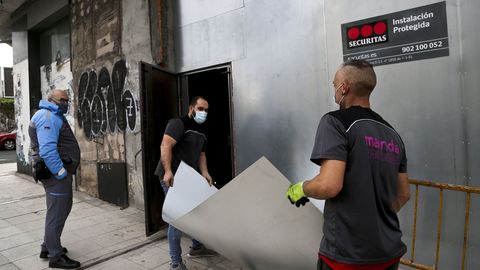 Dos operarios y un vigilante sellando un edificio okupa de Vigo