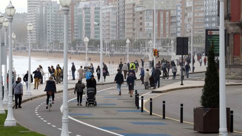 Varias personas caminan por el paseo de la playa de San Lorenzo de Gijn