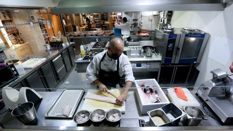 La cocina de Culuca (A Coruña), el sábado por la mañana. Chisco Jiménez, propietario del local, corta pescado mientras dos trabajadores preparan envases y ultiman los detalles de las placas de callos