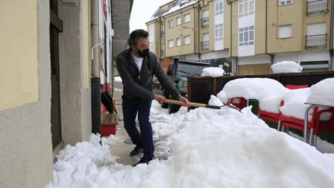 El propietario de la Carnicería Bolaño de O Cadavo retira la nieve decla entrada de su negocio en el que sigue din luz eléctrica