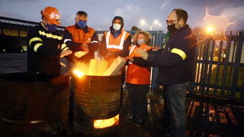 Trabajadores de Alcoa se calientan mientras hacen guardia en el exterior de la fábrica, que está en huelga desde hace dos meses