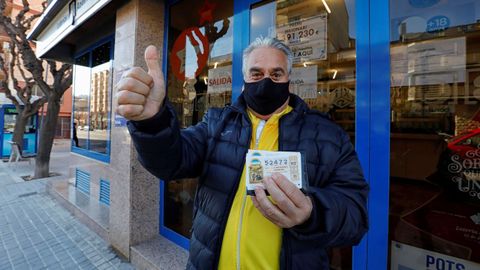 Juan, un vecino de Santa Margarida de Montbui (Barcelona) muestra el décimo premiado con el tercer premio de la Lotería de Navidad ante la administracion del pueblo que ha vendido una serie del 54.472