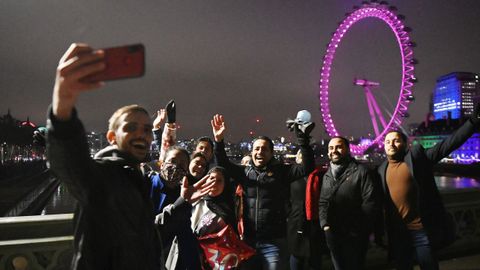 Transentes se toman fotografas en el puente de Wensminster (Londres) para celebrar el cambio de ao
