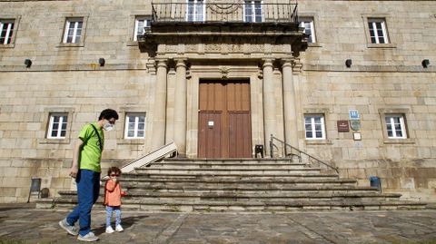 Un hombre pasea el pasado mes de mayo con su hijo junto a la puerta del Parador de Monforte, cerrado en aquel momento por la crisis del coronavirus