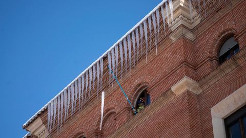 Un bombero retira carámbanos de hielo de la fachada de un edificio en Teruel
