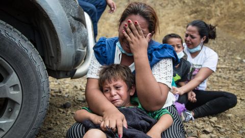 Una mujer y su hijo lloran sentados en el suelo después de que las fuerzas de seguridad de Guatemala disolviesen por la fuerza la caravana de migrantes procedentes de Honduras de la que forman parte