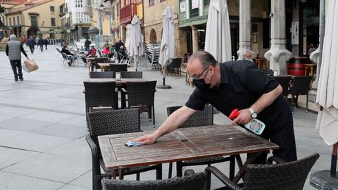 Un camarero desinfecta una mesa de una terraza del centro de Avils