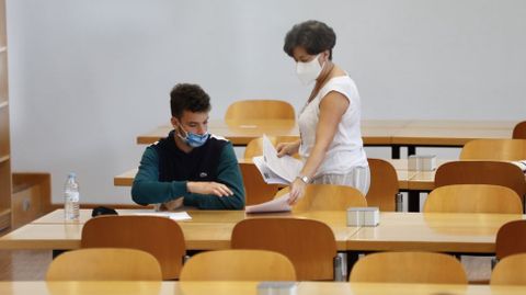 La distancia de seguridad que redujo los aforos de las aulas hizo que la pasada selectividad la relación entre estudiantes y docentes durante las pruebas fuese muy fluida. En la imagen, un alumno de UVigo recibe el examen de una profesora en la ABAU del pasado septiembre