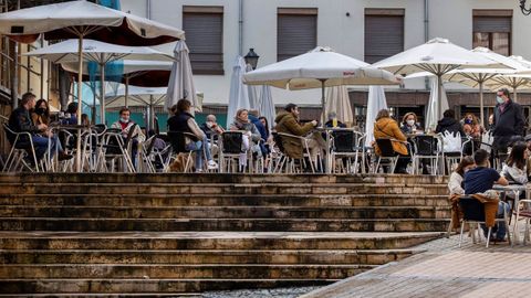 Paseantes en Oviedo. Varias personas disfrutan de la terraza de un bar